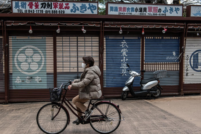 A woman wearing a face mask cycles past closed souvenir shops near Sensoji Temple, normally a popular tourist destination, on Feb. 2 in Tokyo. Prime Minister Yoshihide Suga announced a one-month extension to the state of emergency across much of the country.