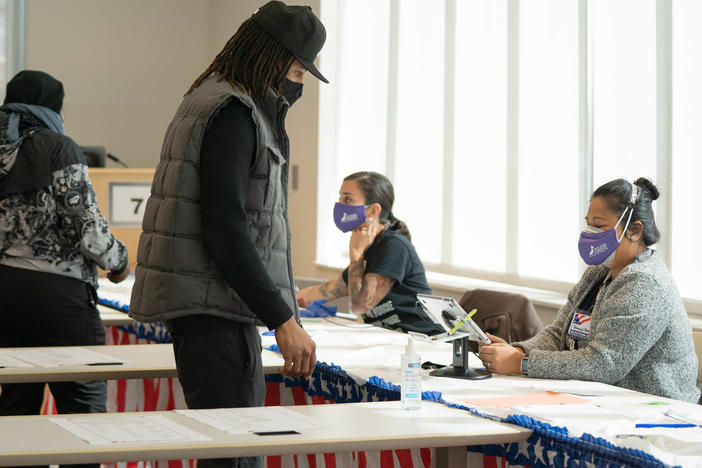 Poll workers help voters get ready to cast their ballots on Nov. 3 in Atlanta. State lawmakers are now considering legislation that could roll back some laws that made it easier for voters to cast ballots by mail.
