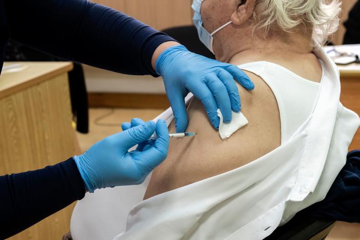 A healthcare worker administers a dose of the coronavirus vaccine to an elderly at a health center in the Cypriot coastal city of Limassol on February 8, 2021.
