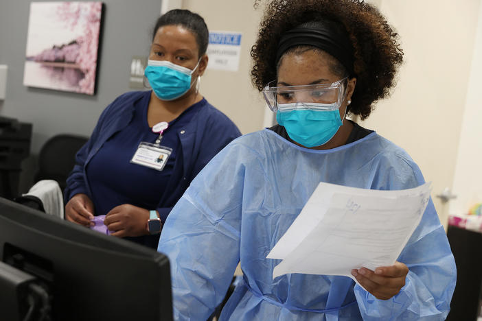Workers at an urgent care facility in Woodbridge, Va., check health records while testing patients for COVID-19 on April 15, 2020.