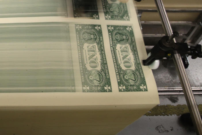 Sheets of one-dollar bills run through the printing press at the Bureau of Engraving and Printing in 2015 in Washington, D.C. Congressional forecasters projected the federal deficit this fiscal year will hit its highest since World War II.