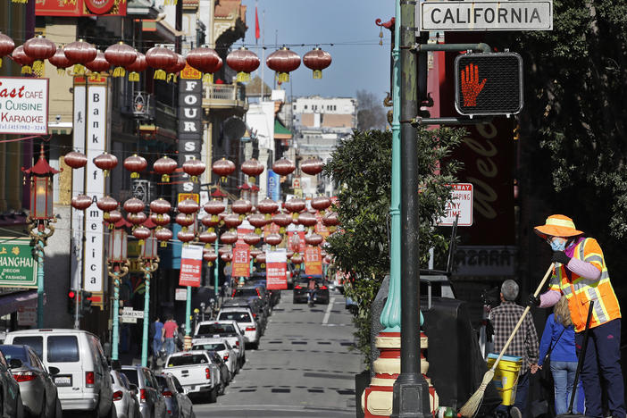 In this Jan. 31, 2020, file photo, a masked worker cleans a street in the Chinatown district in San Francisco. Police and volunteers have increased their street presence after a series of violent attacks against older Asian residents in Bay Area cities stoked fear and subdued the celebratory mood leading up to the Lunar New Year. (AP Photo/Ben Margot, File)