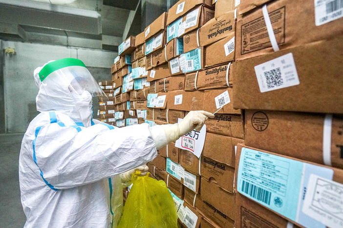 A health officer in a protective suit collects a sample from a package of imported frozen food for a coronavirus rapid test at a wholesale market in China.