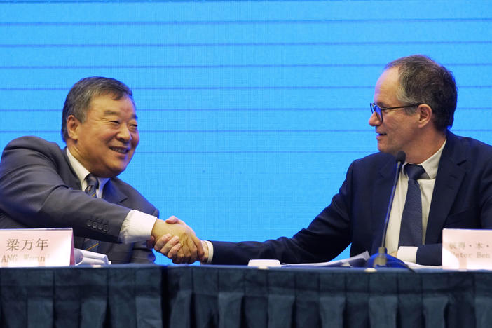 Peter Ben Embarek, of the World Health Organization team (right), shakes hands with Liang Wannian, his Chinese counterpart, after a news conference on Tuesday in Wuhan, China. The White House says it has "deep concerns" over how initial findings were communicated.