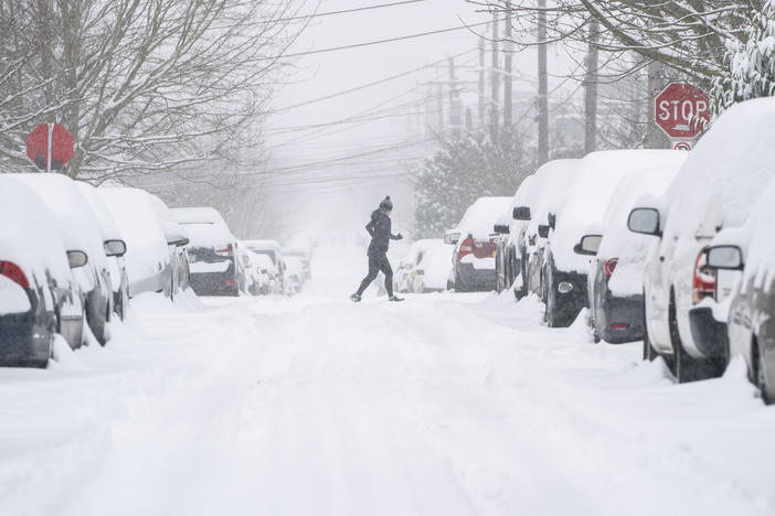 A jogger makes their way across a snowy street on Saturday in Seattle. A large winter storm dropped heavy snow across the region.