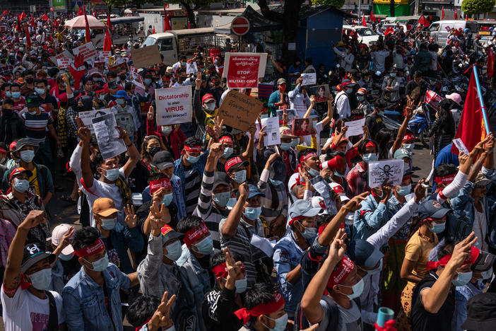 Protesters hold placards and shout slogans on Saturday in Yangon, Myanmar. Myanmar declared martial law in parts of the country, including its two largest cities, as protests continued to draw people to the streets after the military staged a coup.