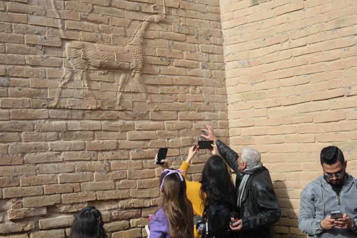 Visitors with the Bil Weekend tourism company take photographs inside the ruins of the ancient city of Babylon, in the area around the Ishtar gate. The animal on the walls ins a dragon-like creature associated with the Babylonian god Marduk.