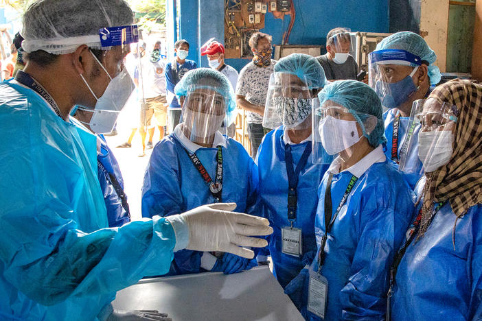 Health workers are briefed before conducting COVID-19 swab tests on public transportation drivers at a slum area in Manila. The Philippines is one of the Southeast Asian countries hit hardest by the pandemic.