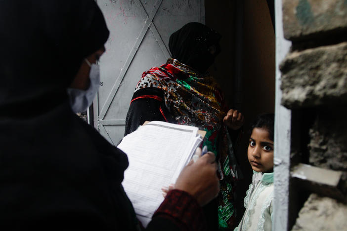 Polio vaccinator Zeenat Parveen, holding the clipboard, and a volunteer go door-to-door to reach children in Rawalpindi, a city near the Pakistani capital of Islamabad.