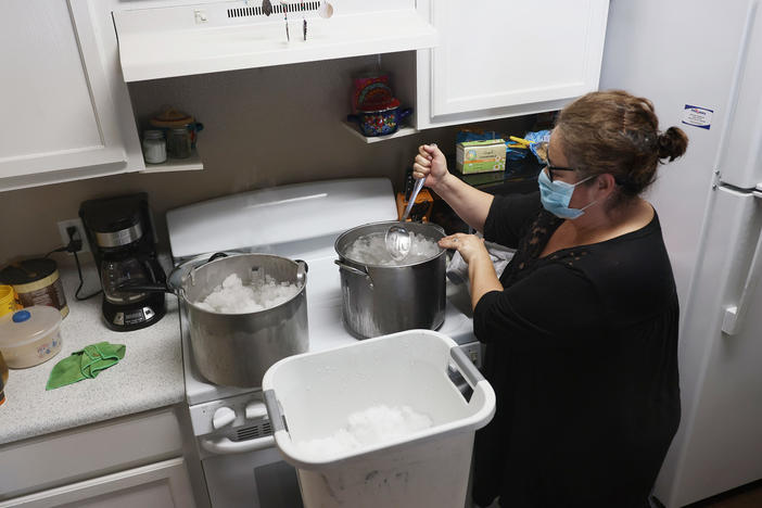 Marie Maybou melts snow on the kitchen stove on Friday in Austin, Texas. She was using the water to flush the toilets in her home after the city water stopped running.
