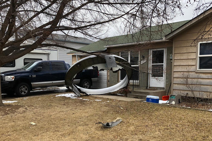 Debris is scattered in the front yard of a house in Broomfield, Colo., on Saturday. A commercial airliner dropped debris in Colorado neighborhoods during an emergency landing.