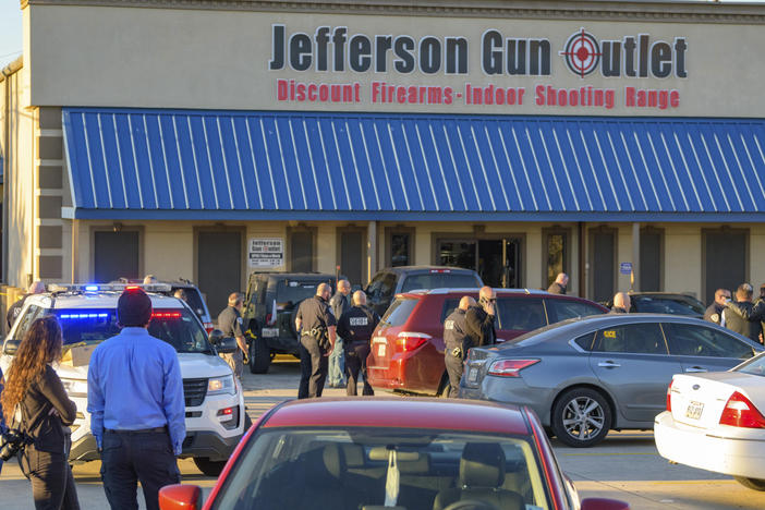 Bystanders gather at the scene of a multiple fatality shooting at the Jefferson Gun Outlet in Metairie, La., Saturday.