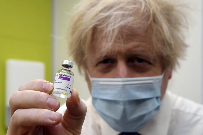 Britain's Prime Minister Boris Johnson holds a vial of the AstraZeneca vaccine during a visit to a coronavirus vaccination center in London on Feb. 15, 2021. The British government hopes to vaccinate all adults by the end of July.