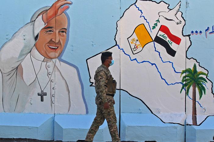 An Iraqi policeman walks by a mural depicting Pope Francis on the outer walls of Our Lady of Salvation Church in Baghdad on Monday. Pope Francis' visit from March 5 to 8 will include trips to Baghdad, the city of Mosul and a meeting with the country's top Shiite cleric Grand Ayatollah Ali al-Sistani.