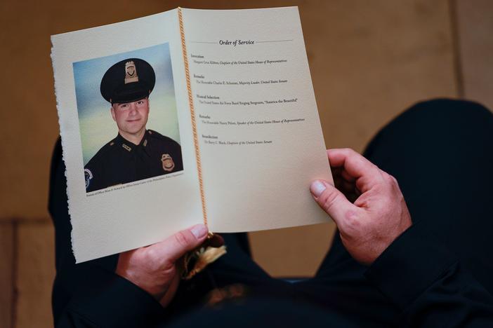 A Capitol Police officer holds a program as people pay their respects at the remains officer Brian Sicknick, who died after defending the Capitol against the Jan. 6 insurrection.