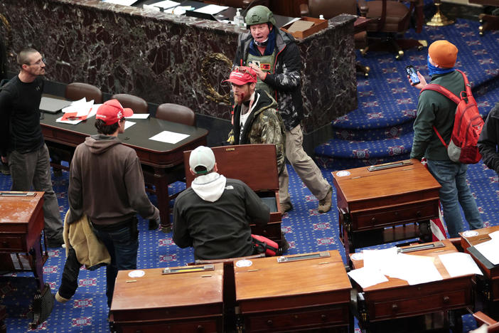 Bruno Cua, 18, is allegedly seen here with his back to the camera, holding a tan jacket. Prosecutors say he entered the Senate Chamber of the U.S. Capitol on Jan. 6 with a handful of other rioters.