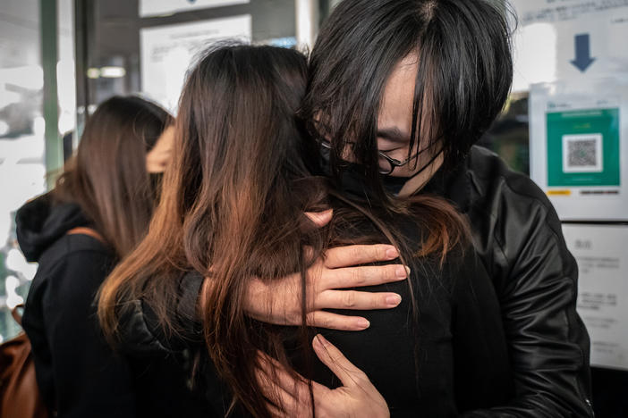 Mike Lam King-nam, who participated in the 2020 pro-democracy primary elections, gives a hug to his wife ahead of reporting to police on Sunday in Hong Kong.