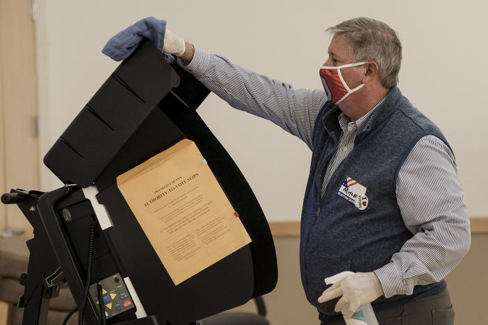 A poll worker sanitizes a voting machine on Nov. 3, 2020 in Columbus, Ohio. Conspiracy theories floated by former President Donald Trump about equipment made by Dominion Voting Systems has led local officials in one Ohio County to slow down the purchase of new Dominion machines.