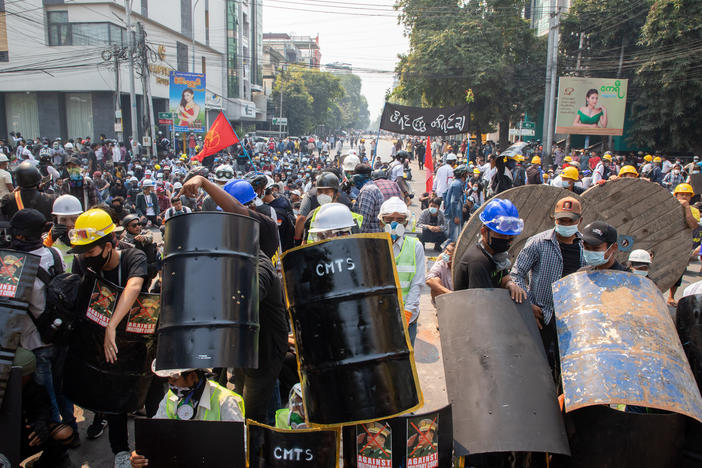 Demonstrators take shelter and block the road during a protest against the military coup in Mandalay, Myanmar on Wednesday.