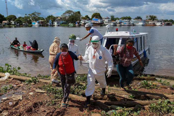 A surge in cases and record high daily death tolls have pushed Brazil into a COVID crisis. Above: Health professionals help patients with symptoms of the new coronavirus on a boat ambulance.