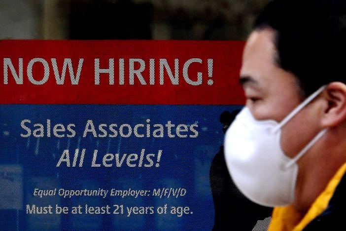 A man walks past a "Now Hiring" sign in front of a store in early December in Arlington, Va. U.S. employers added 379,000 jobs in February, as hiring picked up sharply from the previous month.