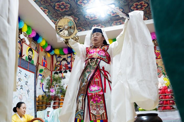 Shaman Jeong Soon-deok holds up a fan, bells and other ceremonial objects during an initiation ceremony at a temple in Seoul.
