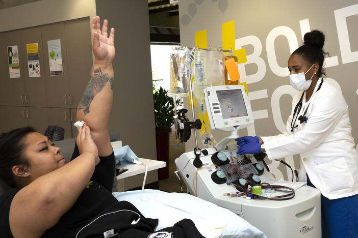 Melissa Cruz elevates her arm after donating COVID-19 convalescent plasma in April 2020 as phlebotomist Jenee Wilson shuts down the collection equipment at Bloodworks Northwest in Seattle.