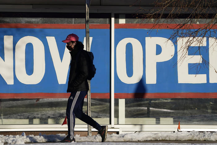 A pedestrian on Feb. 25 walks past the window of a restaurant with a sign promoting its re-opening in Boulder, Colo. Congress on Wednesday passed a $1.9 trillion stimulus plan, which is expected to provide a strong boost to economic growth.