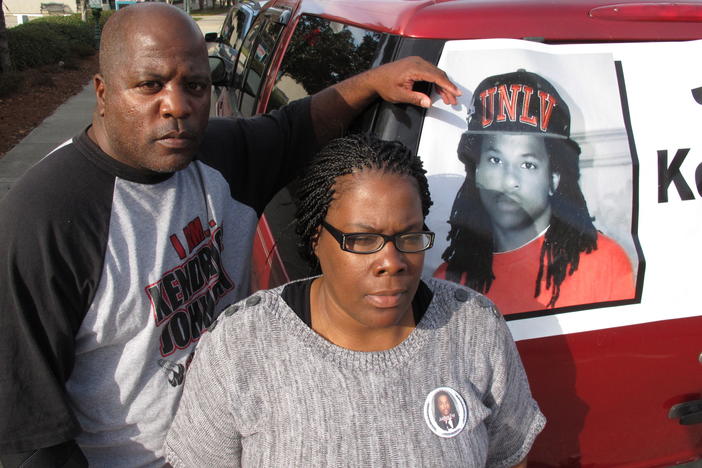 Kenneth and Jacquelyn Johnson stand next to a banner on their SUV showing their late son Kendrick, in Valdosta, Ga., in December 2013. A family spokesperson told NPR they are "cautiously optimistic" after the Lowndes County Sheriff's Office reopened its investigation last week.