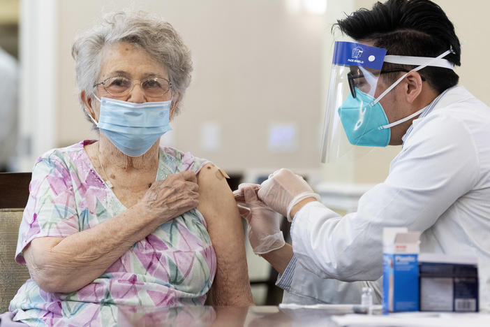 A CVS pharmacist gives the Pfizer/BioNTech COVID-19 vaccine to a resident at the Emerald Court senior living community in Anaheim, Calif., in January. Federal health officials have revised advice on nursing home visitations for the first time since September.