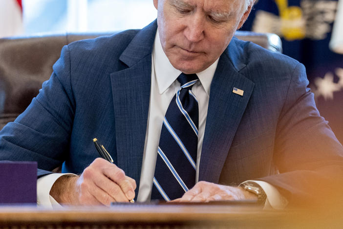 President Biden signs the American Rescue Plan in the Oval Office of the White House on Thursday. Included in the plan is a monthly allowance for many American families that could be a potential financial-life-changer.