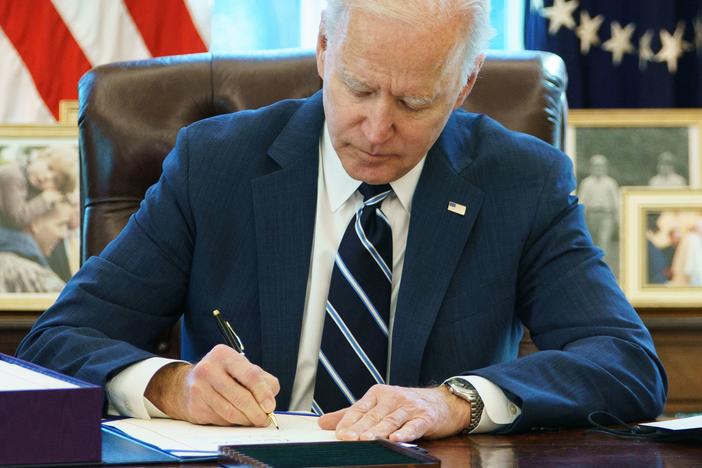 President Biden signs the American Rescue Plan Thursday in the Oval Office. The $1.9 trillion economic stimulus bill includes $1,400 stimulus checks for most Americans.