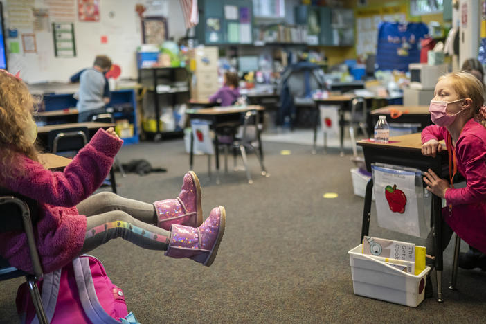 Two first grade students talk in the back of class at the Green Mountain School last month in Woodland, Wash. The CDC's current guidance for schools recommends seating or desks be "at least 6 feet apart when feasible."