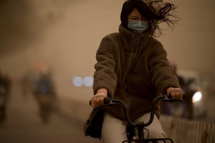 A woman cycles along a street during a sandstorm in Beijing on Monday.