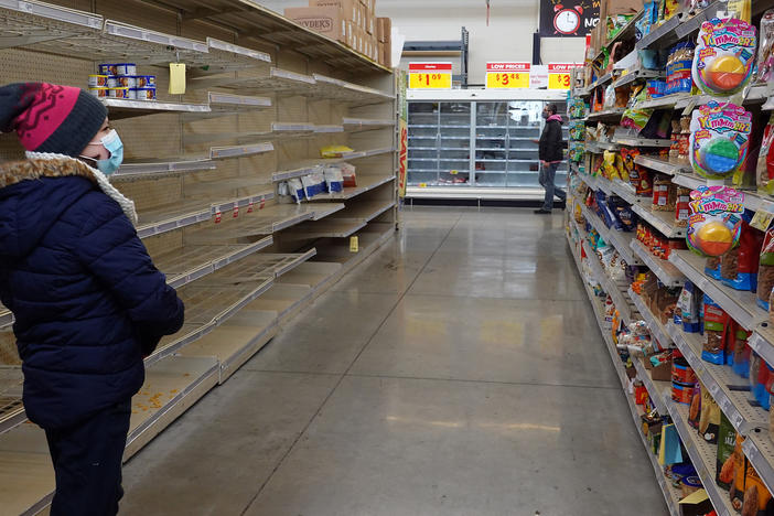 A shopper walks past a mostly bare shelf as people stock up on necessities at the H-E-B grocery store in Austin, Texas, on Feb. 18. A devastating winter storm that hit the middle of the country last month helped send retail sales tumbling.