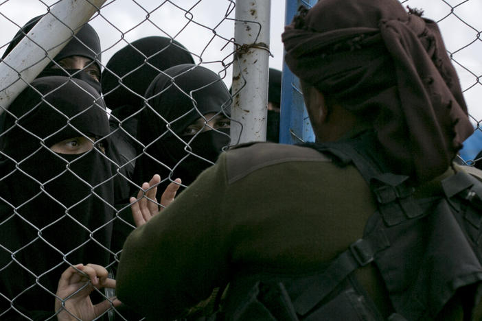 In this March 31, 2019, photo, women speak to guards at the gate that closes off the section for foreign families who lived in the Islamic State's so-called caliphate, at al-Hol camp in Hasakeh province, Syria.