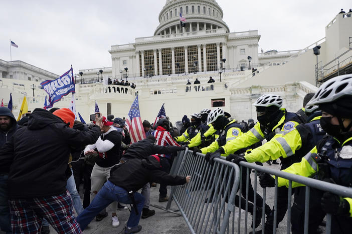 In January, rioters, including many with ties to white supremacists, try to break through a police barrier at the Capitol in Washington.