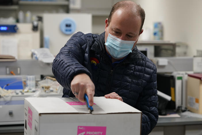 Colorado Gov. Jared Polis opens the shipping box containing the state's first shipment of COVID-19 vaccine at the Colorado Department of Public Health and Environment, Dec. 14, 2020, in east Denver.