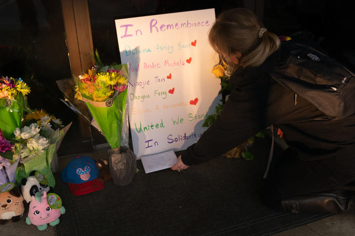 Shelby Swan places a sign outside Youngs Asian Massage, where four people were shot and killed this week in Acworth, Ga. Another four people were fatally shot at two massage businesses in Atlanta, but authorities have not released their names.