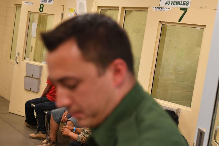 In this file photo, young migrants, whose faces cannot be shown, sit inside a U.S. Customs and Border Protection Facility in Tucson, Arizona.