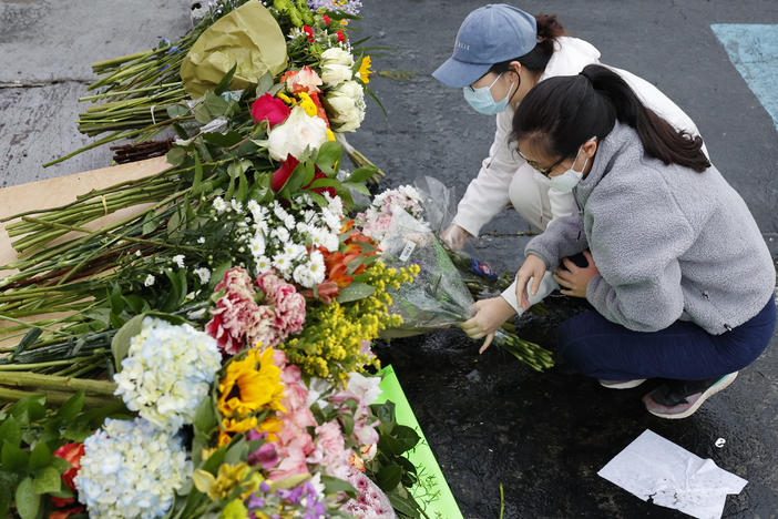 Jenny Choi (left) and Kristi You place flowers Wednesday at the entrance of Gold Spa, one of three locations where deadly shootings happened in the Atlanta area this week.