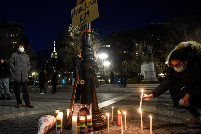 A mourner lights candles for the victims of Tuesday's shootings in Atlanta at a vigil in New York City, one of many across the country this week.