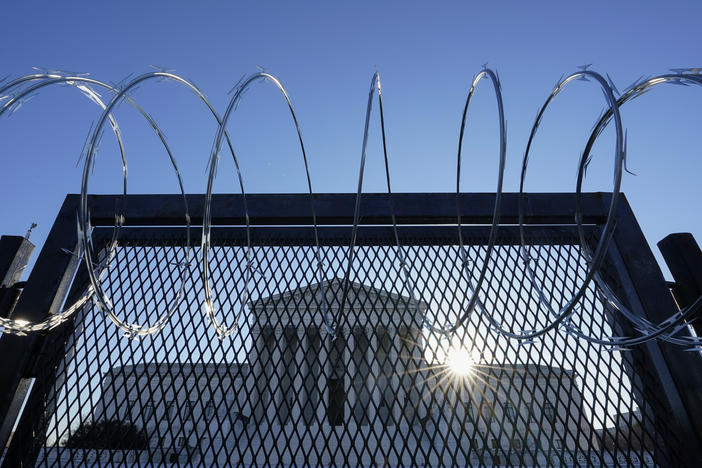 The Supreme Court is seen beyond a razor wire-topped fence at sunrise on March 8.