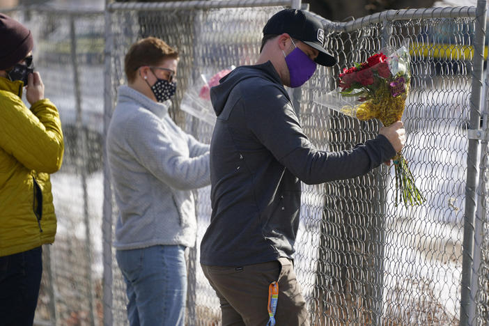 Kiefer Johnson places flowers Tuesday in a makeshift fence around the parking lot outside the King Soopers grocery store in Boulder, Colo., where 10 people were killed a day earlier.