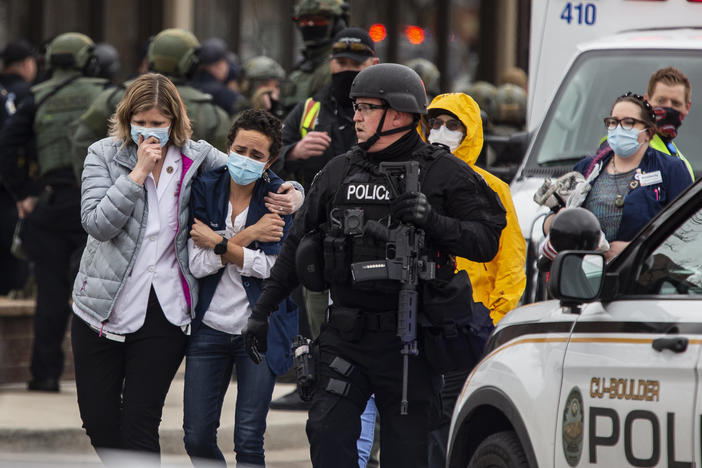 Health care workers walk out of a King Soopers grocery store after a gunman opened fire Monday in Boulder, Colo.