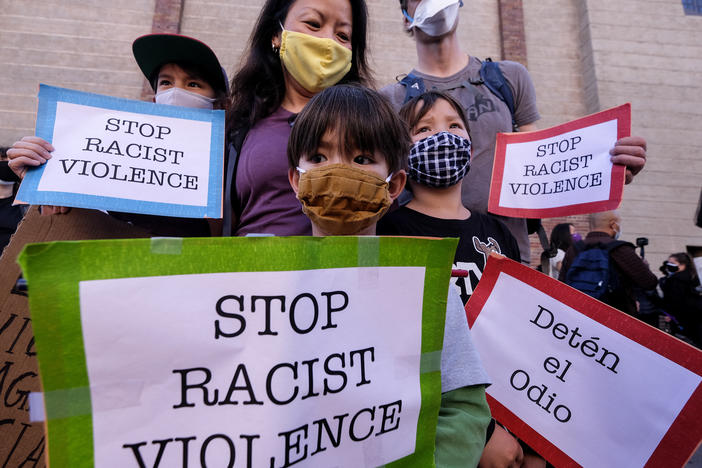 A family wearing face masks and holding signs take part in a rally "Love Our Communities: Build Collective Power" to raise awareness of anti-Asian violence, at the Japanese American National Museum in Little Tokyo in Los Angeles, California, on March 13.