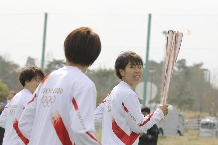 Azusa Iwashimizu (right) and other members of Japan women's national football team run as torchbearers in the first leg of the torch relay for Tokyo Olympics on Thursday in Fukushima prefecture, Japan.