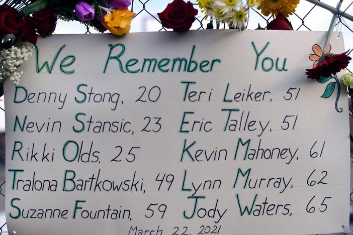A sign framed with flowers lists victims' names on a fence outside a King Soopers grocery store in Boulder, Colo. The suspect in the mass shooting made his first court appearance on Thursday.