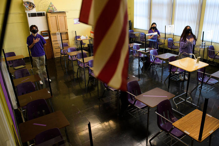 Students stand for the Pledge of Allegiance as they return to in-person learning at St. Anthony Catholic High School in California on March 24. Masks and physical distancing are proving to have some major public health benefits, keeping people from getting all kinds of illnesses, not just COVID-19. But it's unclear whether the strict protocols would be worth the drawbacks in the long run.