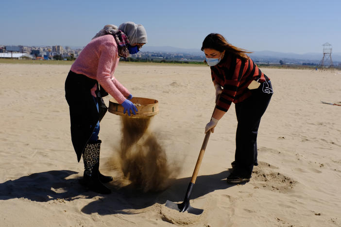 Marine biology student Ranim Tahhan, 21, pictured left, and another volunteer work to clean Tyre beach from the pollution caused by an oil spill in the eastern Mediterranean Sea.